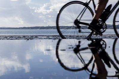 Low section of person riding bicycle by lake
