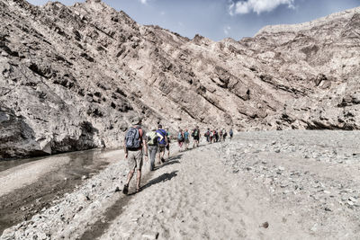 People walking against rocky mountain 