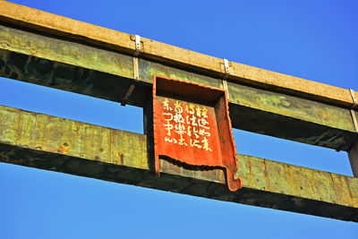 Low angle view of information sign against clear blue sky