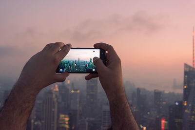 Midsection of man using mobile phone against sky