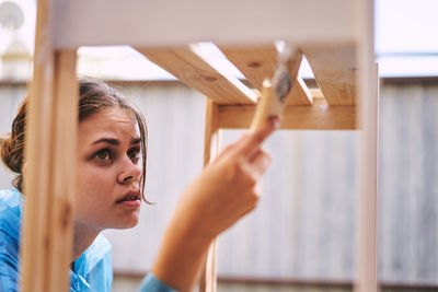 Portrait of young woman sitting on window