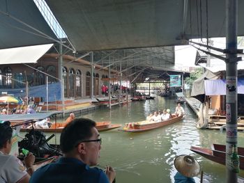 People on boat in canal along buildings