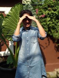 Girl shielding eyes while standing against plants