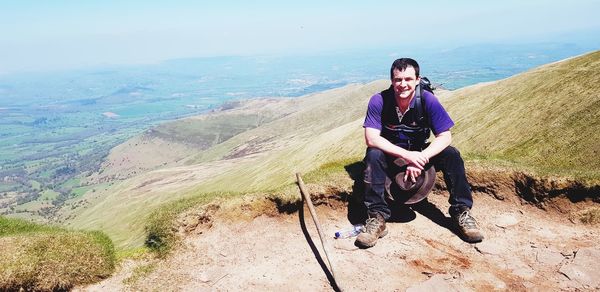 Portrait of smiling man sitting on mountain