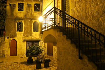 Low angle view of railing by staircase against illuminated buildings