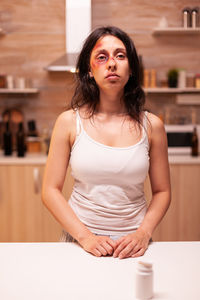 Portrait of young woman standing against wall