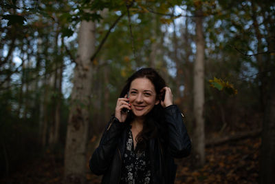Portrait of smiling woman talking on mobile phone in forest