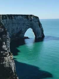 Rock formation in sea against clear sky