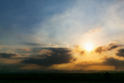 Scenic view of dramatic sky over field during sunset