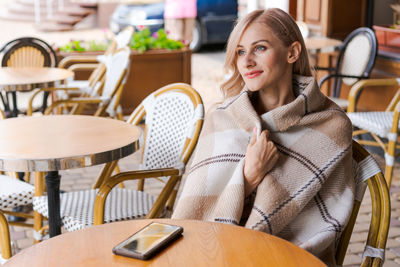 Young woman while relaxing in cafe at table on street, happy caucasian woman