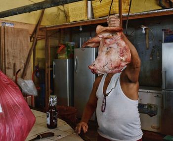 Butcher holding meat over face in kitchen