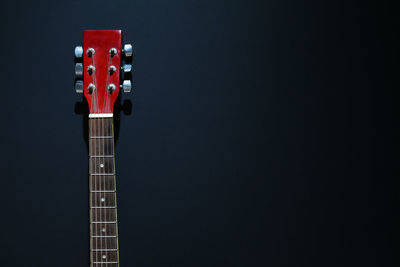 Close-up of acoustic guitar against black background