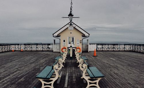 Lifeguard hut on pier by sea against sky