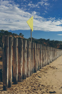 Road sign on sand against sky