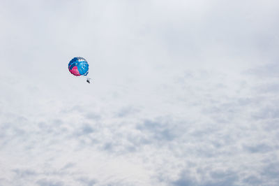 Low angle view of person paragliding against sky