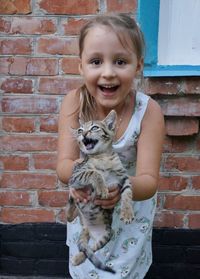 Portrait of smiling girl against brick wall