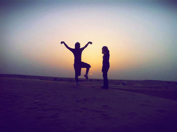 Silhouette friends enjoying at beach during sunset