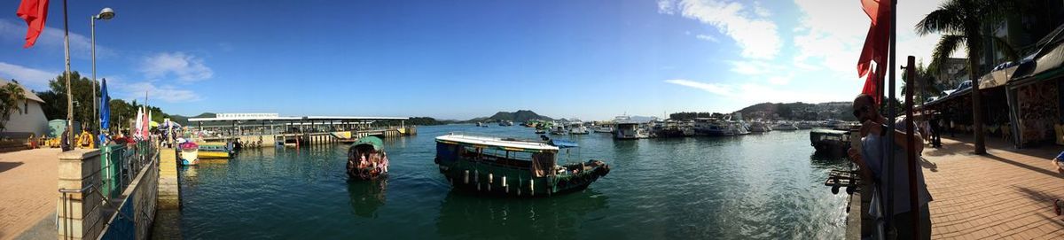 Panoramic view of boats moored in sea against blue sky