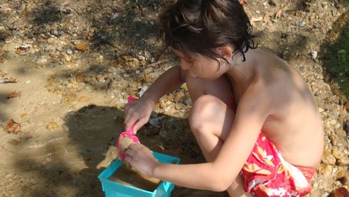 High angle view of boy playing in sand at shore of beach