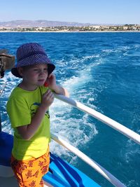High angle view of boy eating lollipop while standing by railing in boat