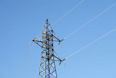 Low angle view of electricity pylon against blue sky