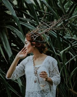 Young woman looking away while standing against plants