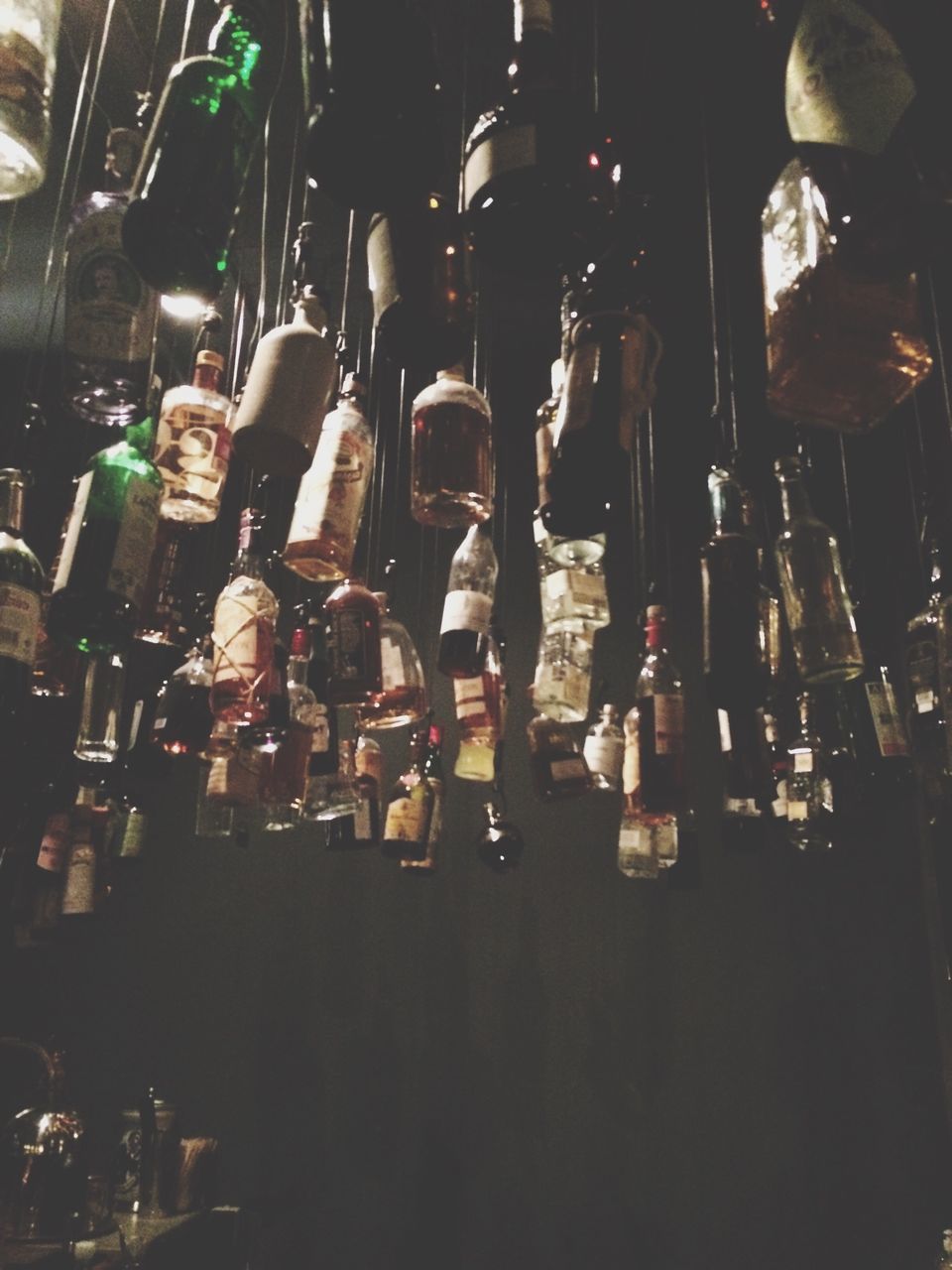 indoors, large group of objects, in a row, still life, variation, arrangement, abundance, order, side by side, choice, hanging, bottle, glass - material, collection, repetition, group of objects, close-up, no people, illuminated, shelf