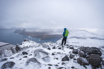 Rear view of person standing on snowcapped mountain