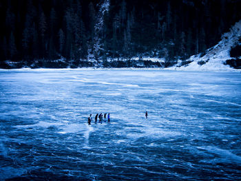 Silhouette people ice-skating on frozen lake