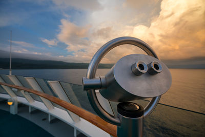 Coin-operated binoculars by sea against sky