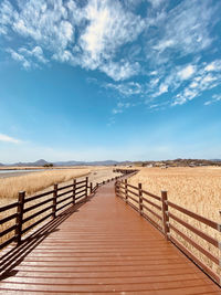 Boardwalk leading towards sea against sky