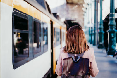 Woman walking by train on railroad station platform