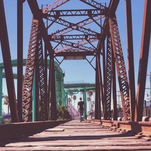 Rear view of man walking on bridge