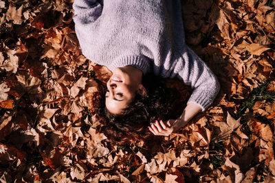 High angle view of girl lying on dry leaves