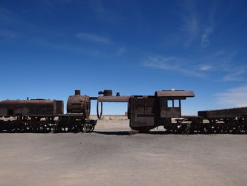 Abandoned train on field against blue sky