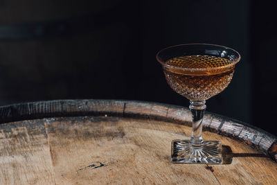 Whiskey cocktail in vintage hobnail glass atop wooden barrel