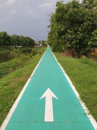 Road sign on field against sky