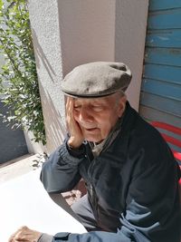 Senior man wearing hat sitting outdoors