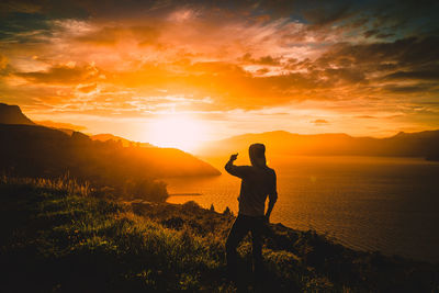 Silhouette man standing on mountain against sky during sunset