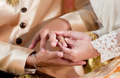 Midsection of wedding couple exchanging finger rings during ceremony