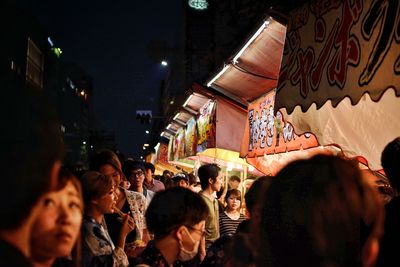 Crowd in illuminated city against sky at night