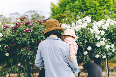 Rear view of people walking on flowering plants