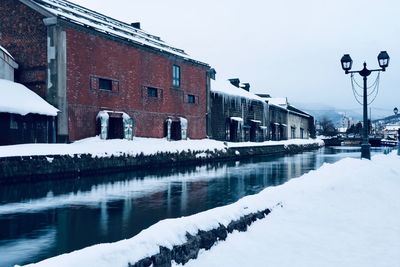 Canal amidst buildings against sky during winter