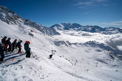 People on snowcapped mountains against sky