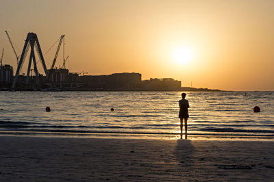 Silhouette of man at beach against sky during sunset