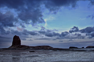 Rock formations on beach against sky