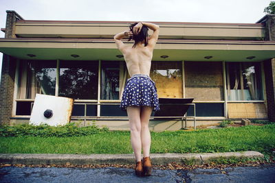 Full length of young woman standing against building