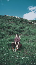 Man sitting on field against sky