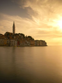 View of buildings by sea against sky during sunset