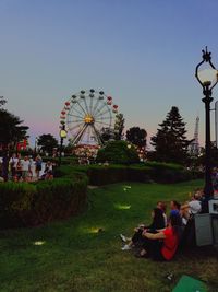 People at amusement park against clear sky